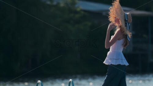 Chisinau, Moldova – June 17, 2025: Woman in a wide-brimmed straw hat with a ribbon, soaking in the late afternoon light - Starpik Stock