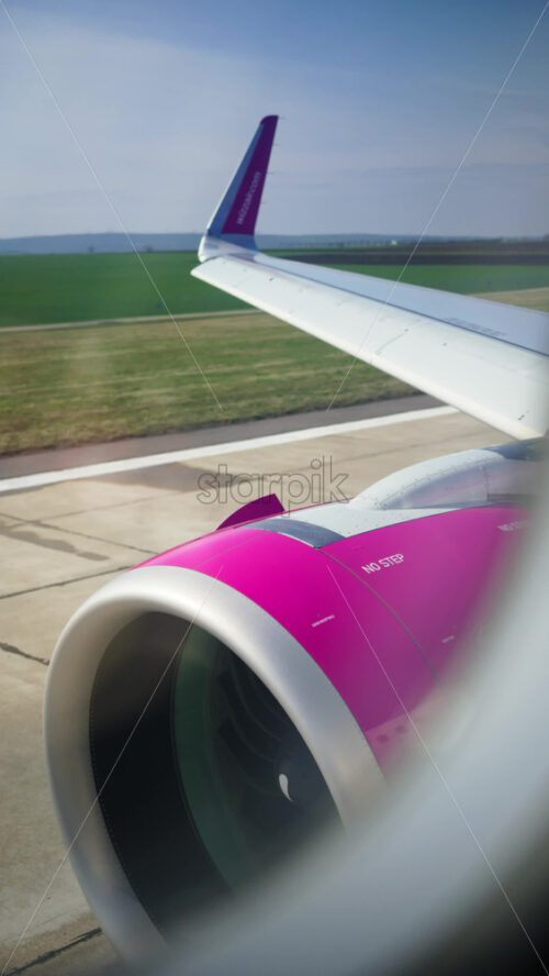 Chisinau, Moldova – March 20, 2025: View from an airplane window of a WizzAir airplane taking of at the airport. Vertical - Starpik Stock