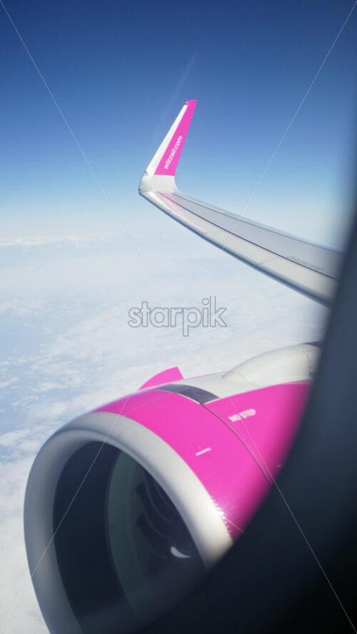 Chisinau, Moldova – March 20, 2025: View of the turbine and wing of a WizzAir airplane from the window. Vertical - Starpik Stock