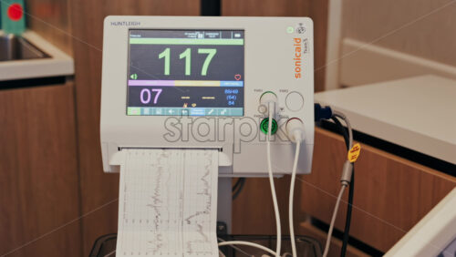 Chisinau, Moldova – May 31, 2025: Close-up of a fetal monitor in a doctor’s office, displaying fetal heart rate and uterine contraction data during a prenatal check-up - Starpik Stock
