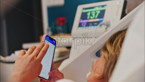 Chisinau, Moldova – May 31, 2025: Pregnant woman scrolling on her phone while doing a prenatal check-up at the doctor’s office - Starpik Stock