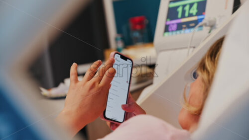 Chisinau, Moldova – May 31, 2025: Pregnant woman using the iHerb app on her phone while doing a prenatal check-up at the doctor’s office - Starpik Stock