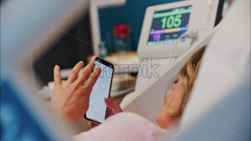 Chisinau, Moldova – May 31, 2025: Pregnant woman using the iHerb app on her phone while doing a prenatal check-up at the doctor’s office - Starpik Stock