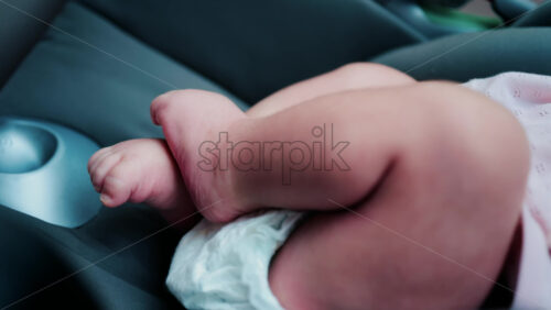 Close up of a baby legs and tiny hands while sitting in a stroller - Starpik Stock