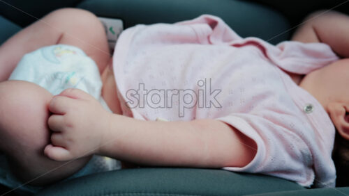 Close up of a baby legs and tiny hands while sitting in a stroller - Starpik Stock