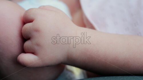 Close up of a baby legs and tiny hands while sitting in a stroller - Starpik Stock