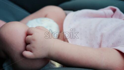 Close up of a baby legs and tiny hands while sitting in a stroller - Starpik Stock