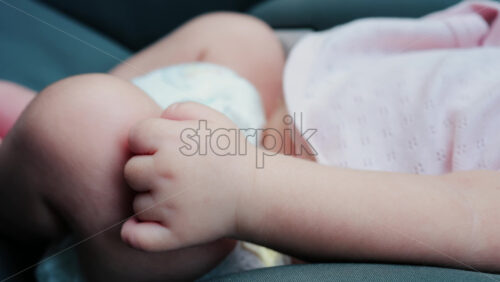 Close up of a baby legs and tiny hands while sitting in a stroller - Starpik Stock