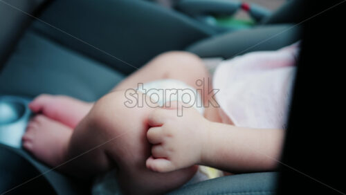 Close up of a baby legs and tiny hands while sitting in a stroller - Starpik Stock