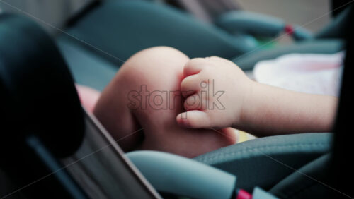 Close up of a baby legs and tiny hands while sitting in a stroller - Starpik Stock