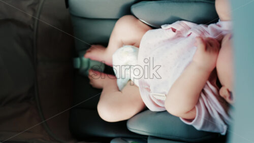 Close up of a baby wearing a pink outfit, peacefully sleeping in a stroller - Starpik Stock