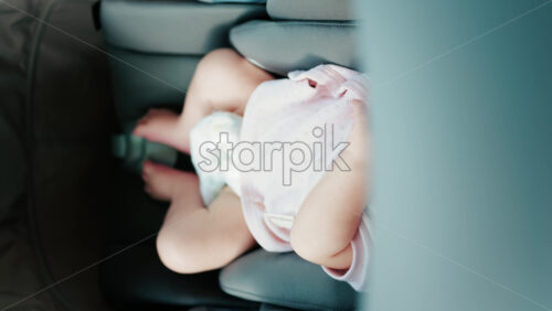 Close up of a baby wearing a pink outfit, peacefully sleeping in a stroller - Starpik Stock