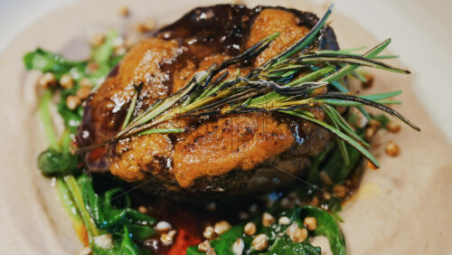 Close up of a beautifully plated beef filet, topped with a golden crust and garnished with rosemary - Starpik Stock