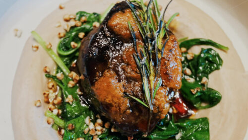 Close up of a beautifully plated beef filet, topped with a golden crust and garnished with rosemary - Starpik Stock