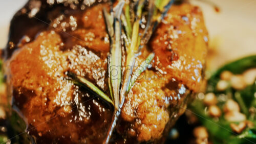 Close up of a beautifully plated beef filet, topped with a golden crust and garnished with rosemary - Starpik Stock