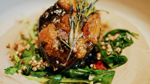 Close up of a beautifully plated beef filet, topped with a golden crust and garnished with rosemary - Starpik Stock
