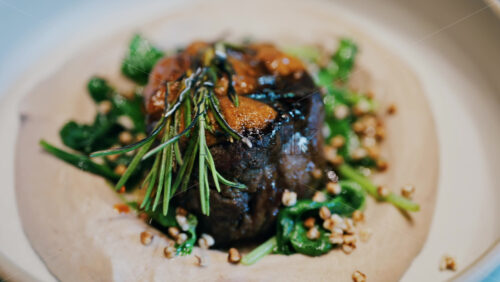 Close up of a beautifully plated beef filet, topped with a golden crust and garnished with rosemary - Starpik Stock
