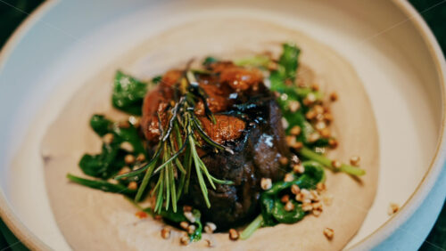 Close up of a beautifully plated beef filet, topped with a golden crust and garnished with rosemary - Starpik Stock