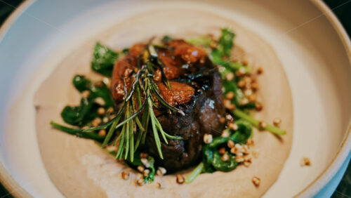 Close up of a beautifully plated beef filet, topped with a golden crust and garnished with rosemary - Starpik Stock