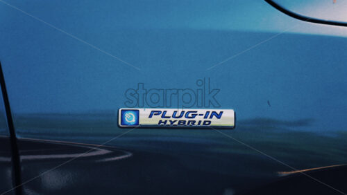 Close up of a blue car with a “Plug-In Hybrid” emblem on it - Starpik Stock