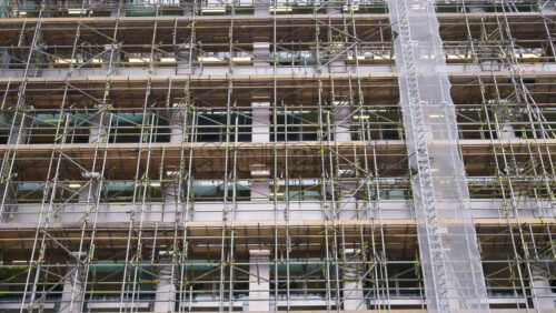 Close-up of a building facade covered in scaffolding and protective mesh during construction or renovation - Starpik Stock