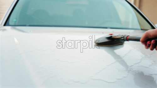 Close up of a car hood being scrubbed with a brush and water - Starpik Stock