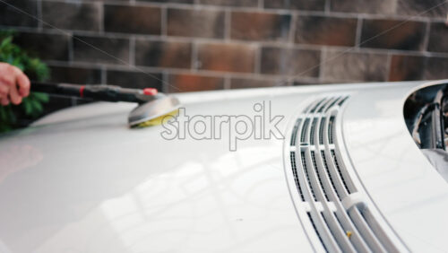 Close up of a car hood being scrubbed with a brush and water - Starpik Stock