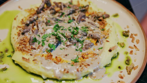 Close up of a creamy mushroom sauce over mashed potatoes on a plate at a restaurant - Starpik Stock