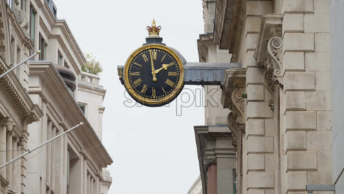 Close-up of a decorative black and gold clock mounted on a historic stone building in London, England - Starpik Stock