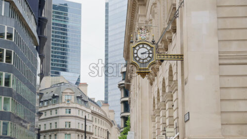 Close-up of a decorative white and gold clock mounted on a historic stone building in London, England - Starpik Stock