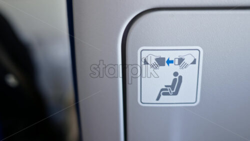 Close up of a fasten the seat belt sign on the back of an airplane seat - Starpik Stock