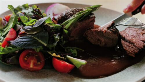 Close up of a filet mignon with a red wine sauce and a fresh salad garnish - Starpik Stock