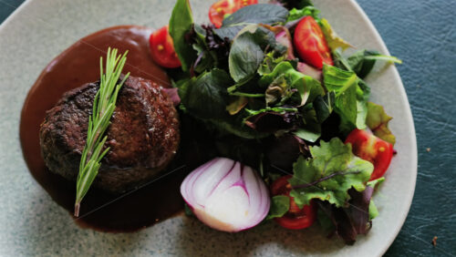 Close up of a filet mignon with a red wine sauce and a fresh salad garnish - Starpik Stock