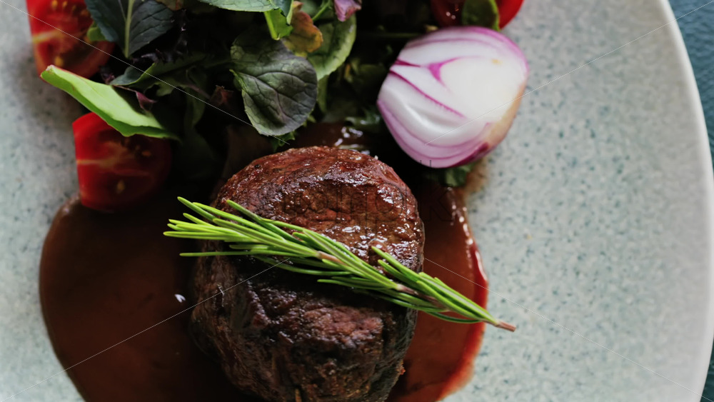 Close up of a filet mignon with a red wine sauce and a fresh salad garnish - Starpik Stock