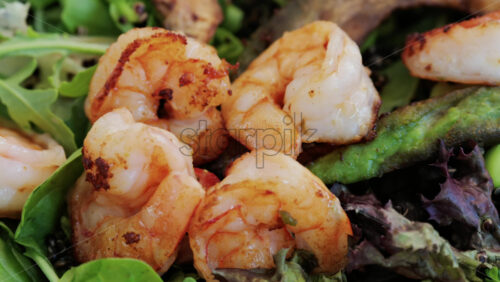 Close up of a fresh salad topped with grilled shrimp, leafy greens, avocado, and vegetables, perfect for healthy eating - Starpik Stock