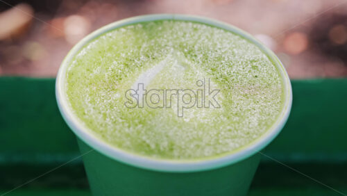 Close up of a frothy matcha latte with heart-shaped latte art - Starpik Stock
