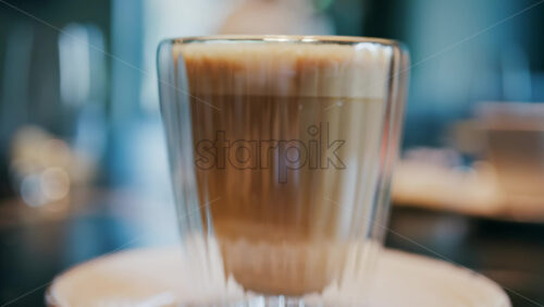 Close up of a glass cup with a latte at a cafe - Starpik Stock