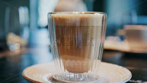Close up of a glass cup with a latte at a cafe - Starpik Stock