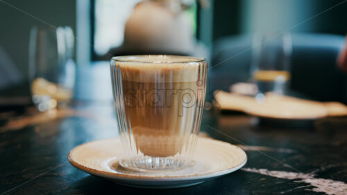 Close up of a glass cup with a latte at a cafe - Starpik Stock