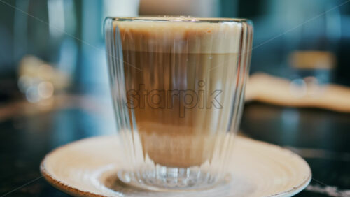 Close up of a glass cup with a latte at a cafe - Starpik Stock