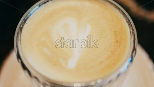 Close up of a glass cup with a latte at a cafe - Starpik Stock