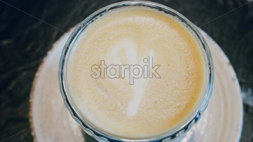 Close up of a glass cup with a latte at a cafe - Starpik Stock