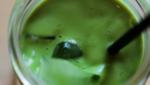 Close up of a glass of an iced matcha on a table at a cafe - Starpik Stock