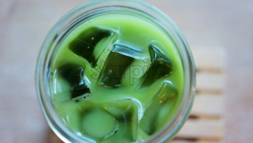 Close up of a glass of an iced matcha on a table at a cafe - Starpik Stock