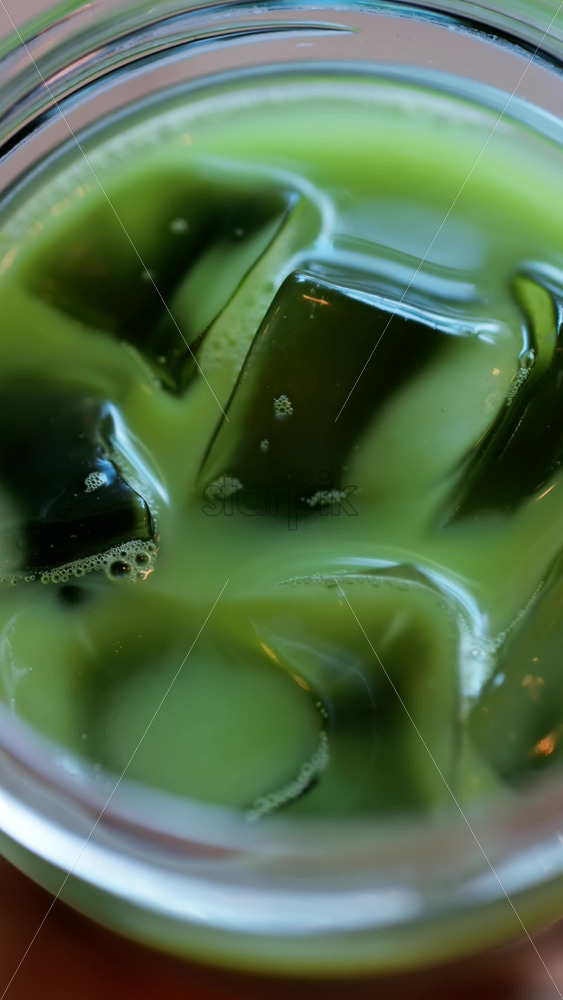 Close up of a glass of an iced matcha on a table at a cafe. Vertical - Starpik Stock