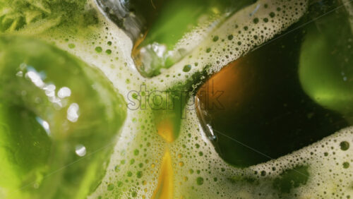 Close up of a glass of an iced orange juice matcha on a table at a cafe - Starpik Stock