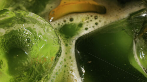 Close up of a glass of an iced orange juice matcha on a table at a cafe - Starpik Stock