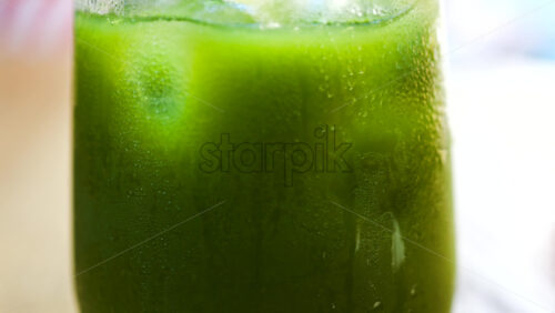 Close up of a glass of an iced orange juice matcha on a table at a cafe - Starpik Stock