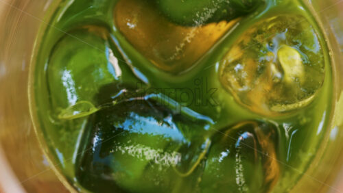 Close up of a glass of an iced orange juice matcha on a table at a cafe - Starpik Stock