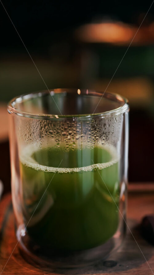 Close up of a glass of green tea on a table. Vertical - Starpik Stock
